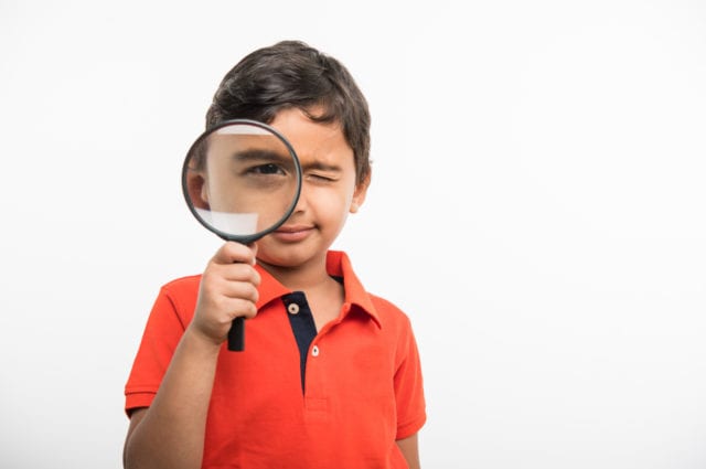 small boy looking through magnifying glass