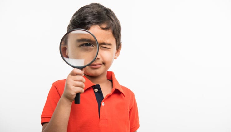 small boy looking through magnifying glass