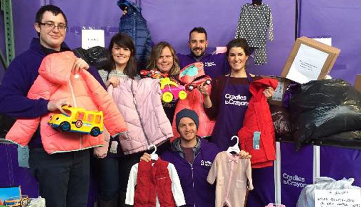 Volunteers in purple aprons collect children's items for a donation drive