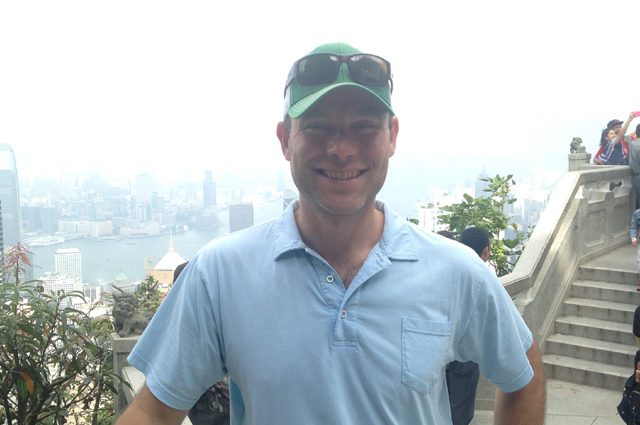 Happy man stands with Hong Kong skyline behind