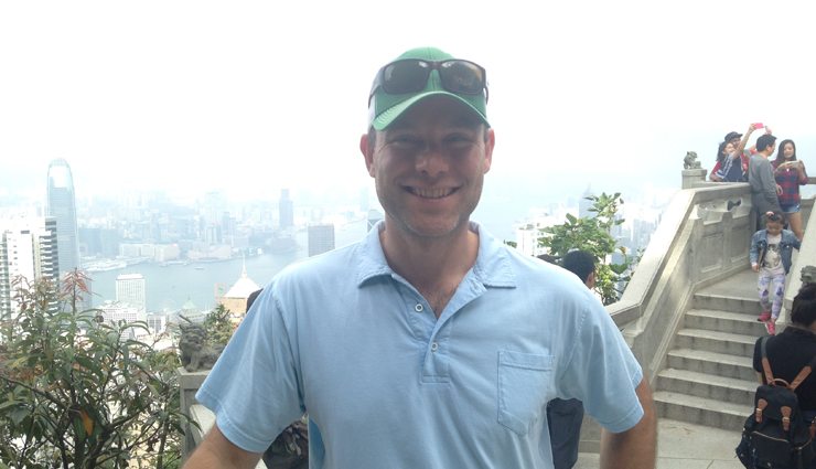 Happy man stands with Hong Kong skyline behind