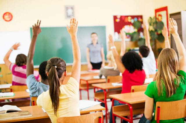 classroom of students raising hands