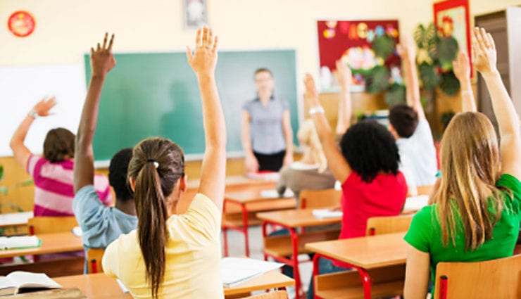 classroom of students raising hands