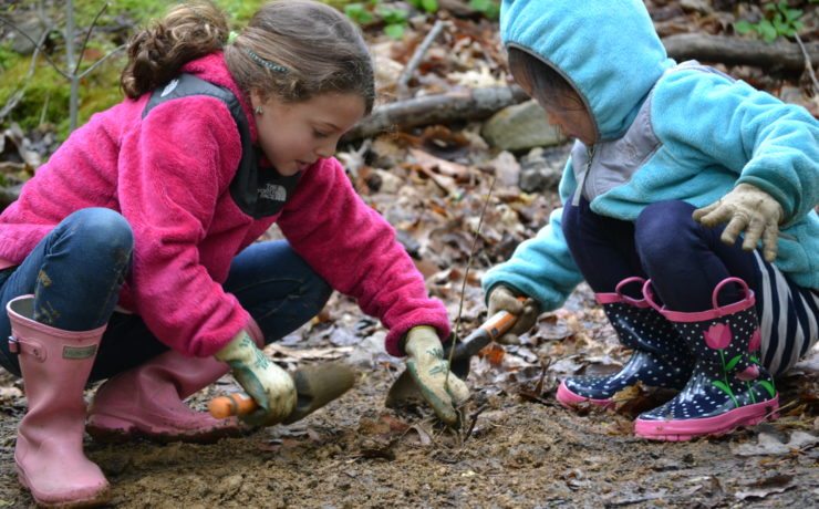 Two young students dig in the mud