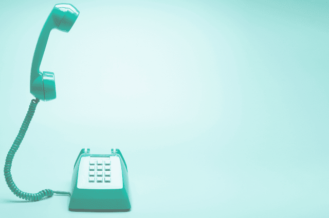 image of a teal landline phone with the phone receiver floating above the phone base