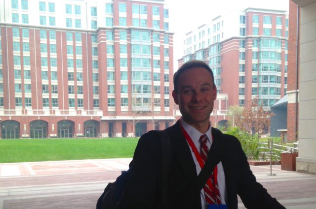 happy man in suit outside red building
