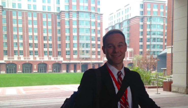 happy man in suit outside red building