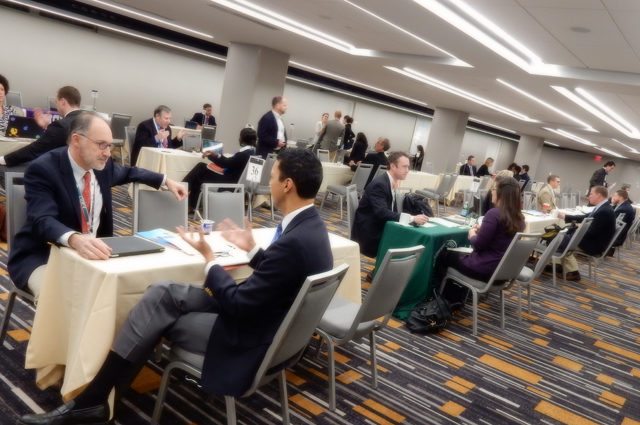 Businessmen and women interview in a large room full of tables