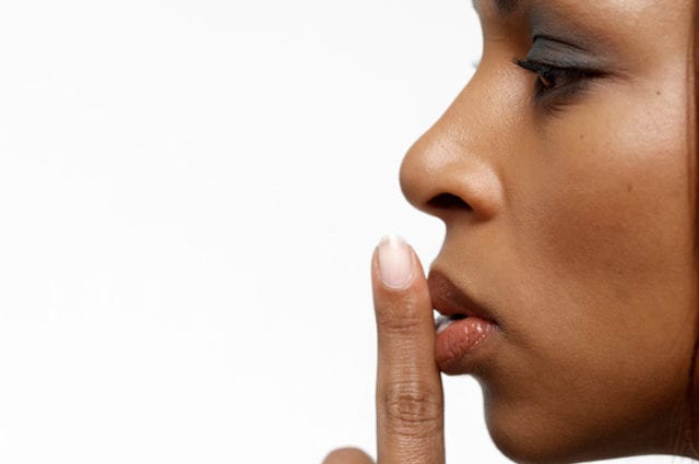 profile of woman holding finger to mouth to hush