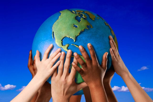 children's arms and hands of varying shades hold a globe