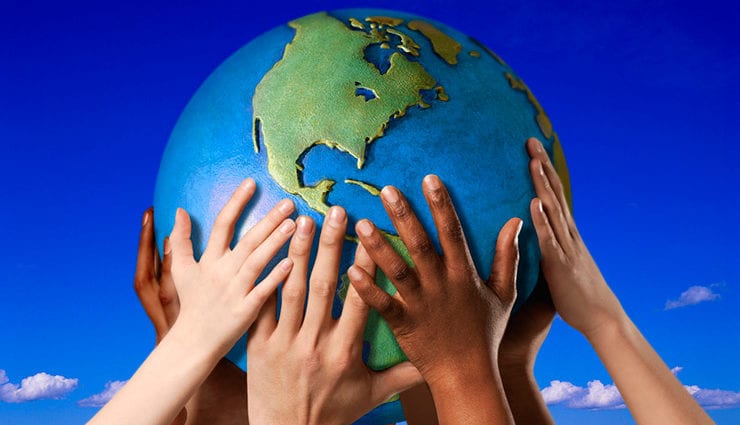 children's arms and hands of varying shades hold a globe