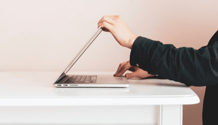 Frame of a person's hands closing a laptop on a table