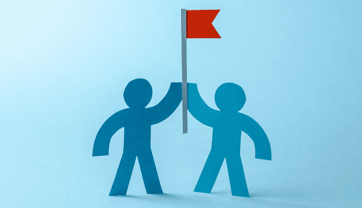 two paper cutouts of people holding up a red flag together in support