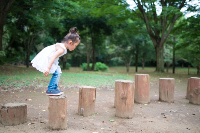 Small girl standing on wood stumps