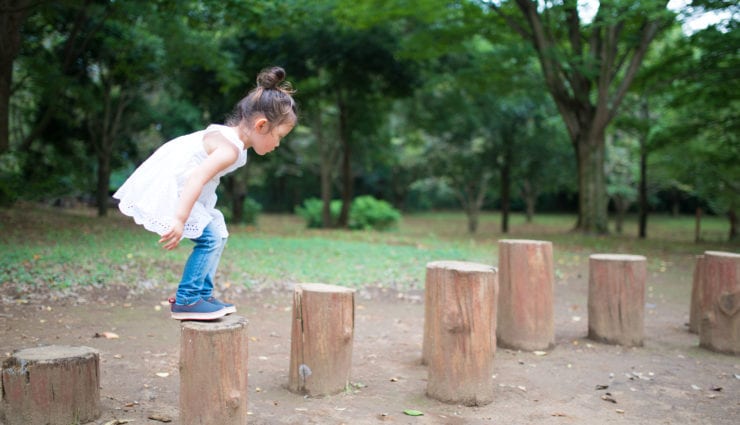 Small girl standing on wood stumps