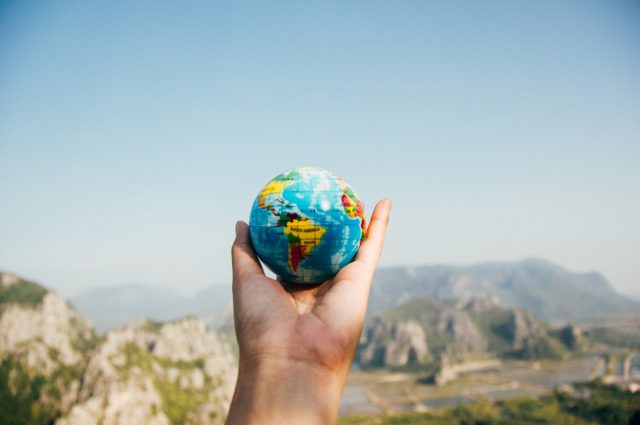 Outstretched hand holding a globe with mountains in background