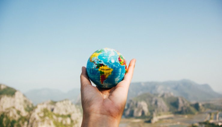 Outstretched hand holding a globe with mountains in background