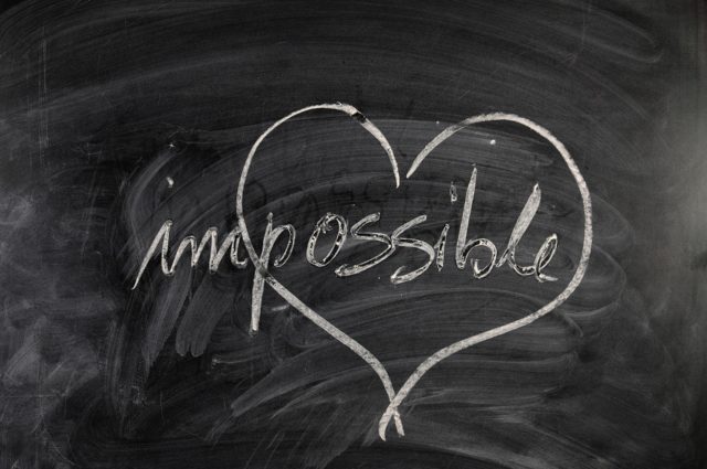 The word impossible written on a chalkboard with a heart drawn around possible