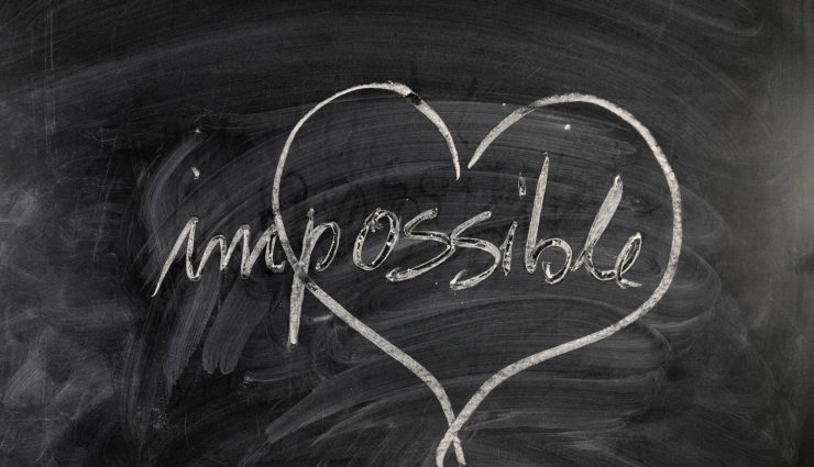 The word impossible written on a chalkboard with a heart drawn around possible