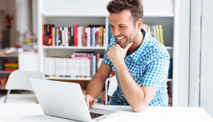 Man in gingham shirt smiling at laptop