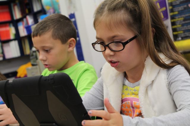 Young girl and boy using iPads