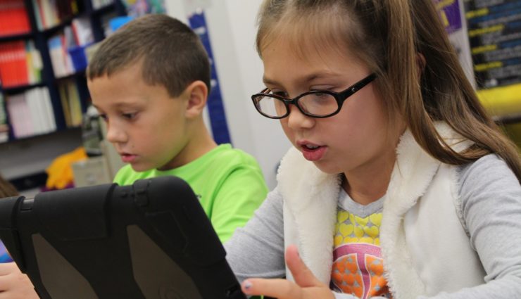 Young girl and boy using iPads