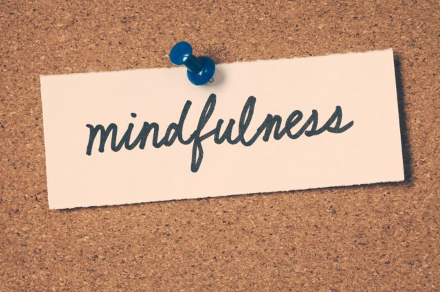 Mindfulness written on a piece of paper pinned to a corkboard