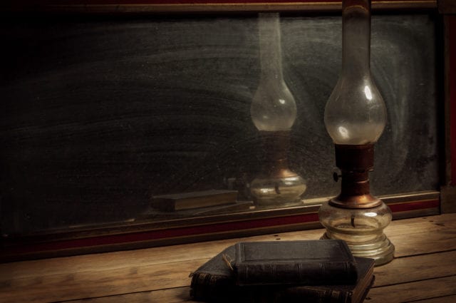 Old vintage mirror, oil lamp with old books on wooden table