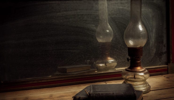 Old vintage mirror, oil lamp with old books on wooden table