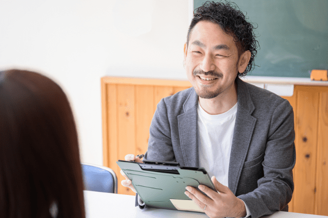 Asian man sitting across a desk smiling at interviewer