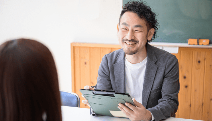 Asian man sitting across a desk smiling at interviewer