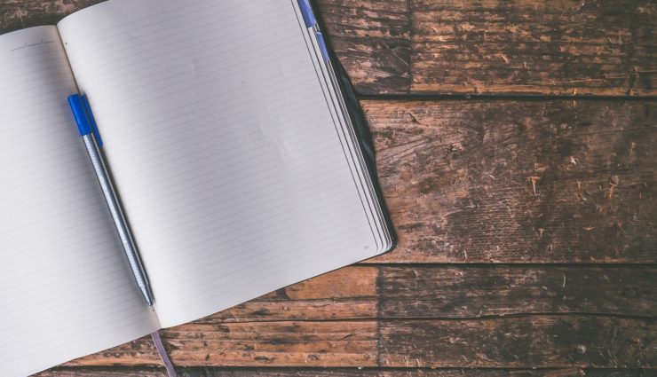 Open notebook sitting on a wood table.