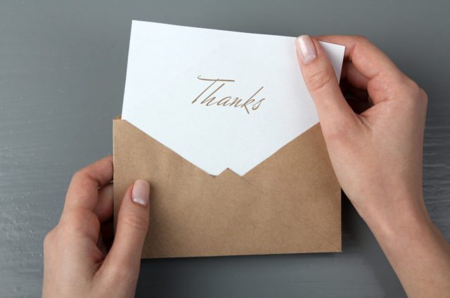 Hands removing a thank you note from an envelope