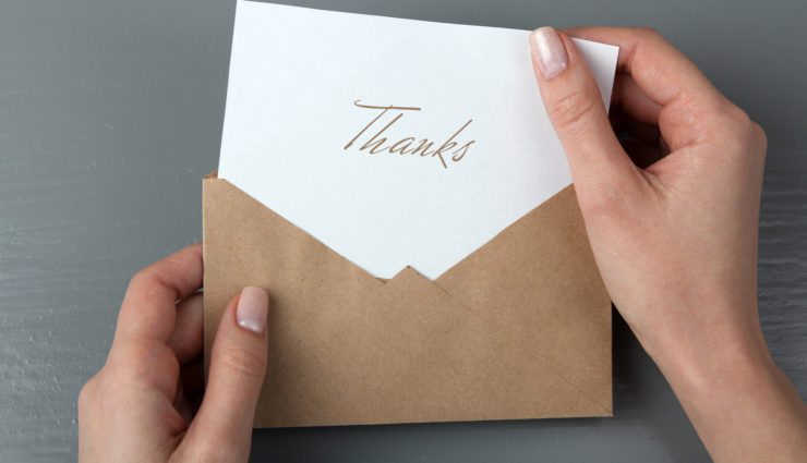 Hands removing a thank you note from an envelope