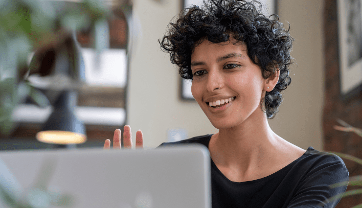 person with short hair facing a computer screen waving