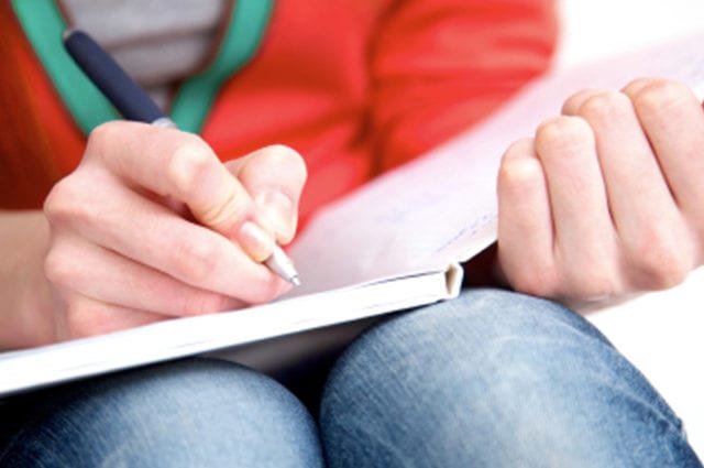 Female student close up writing in notebook with pen