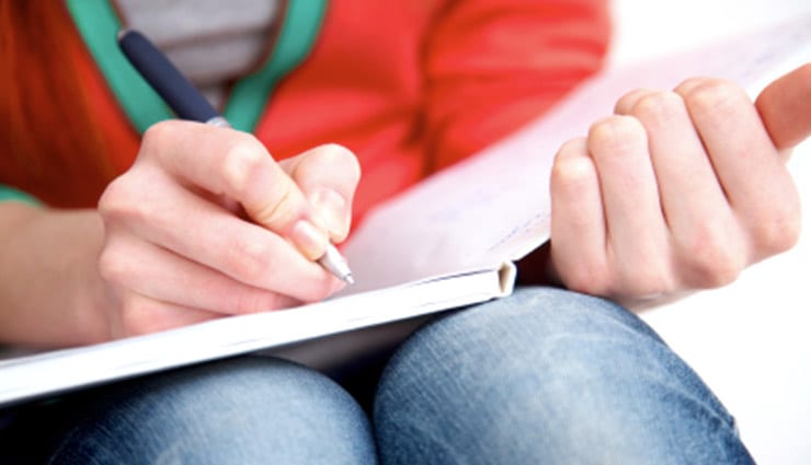 Female student close up writing in notebook with pen