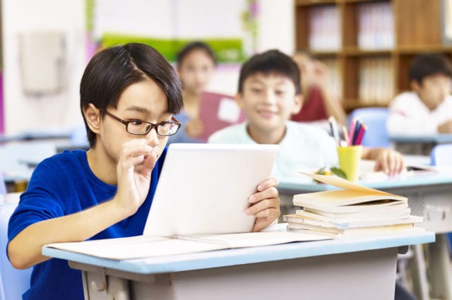 elementary schoolboy looking with curiosity at a tablet computer
