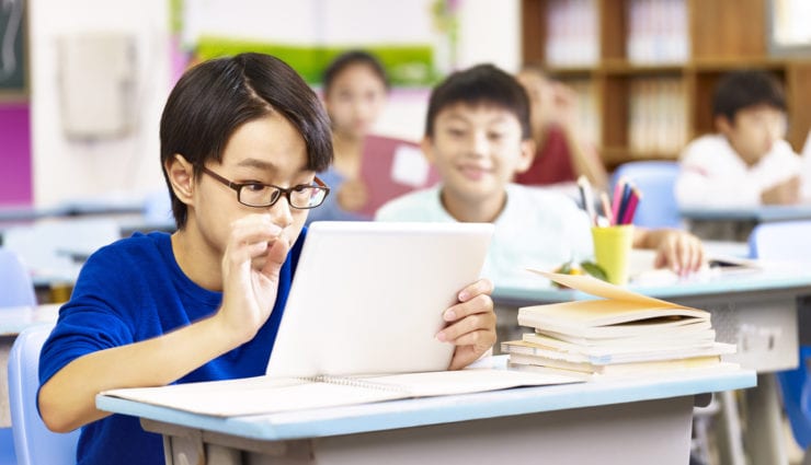 elementary schoolboy looking with curiosity at a tablet computer