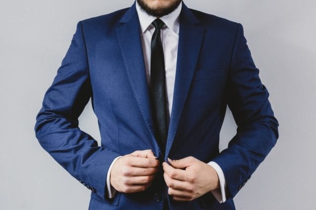business man puts on his blue suit jacket