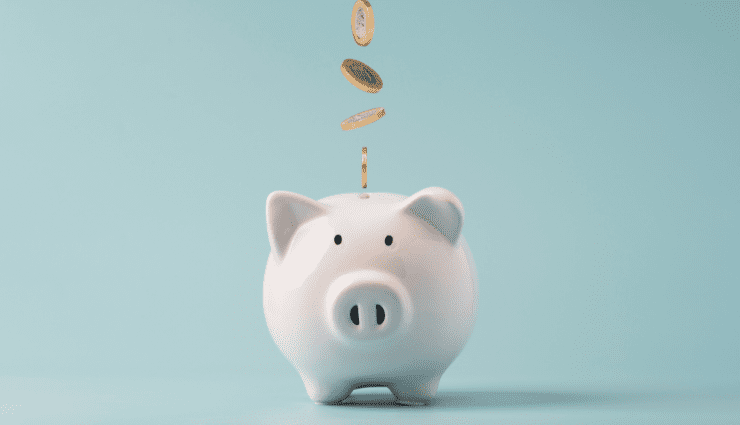 white ceramic piggy bank with gold coins falling down into it