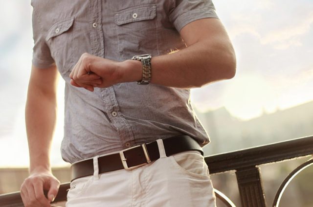 cropped image of man's torso and he checks wristwatch