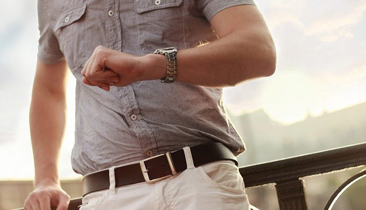 cropped image of man's torso and he checks wristwatch