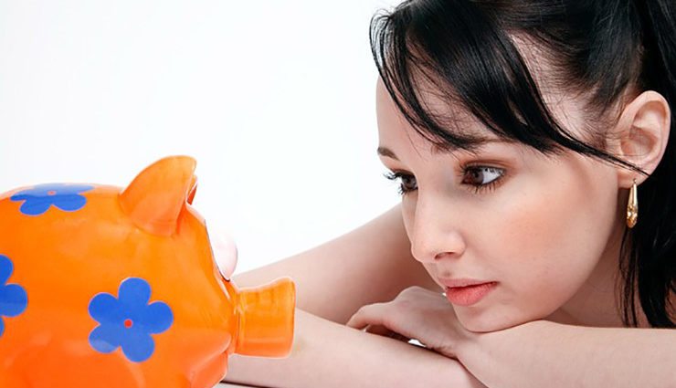 woman stares at orange and blue flowered piggy bank