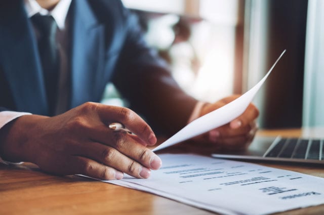 Person with resume in one hand and pen in the other