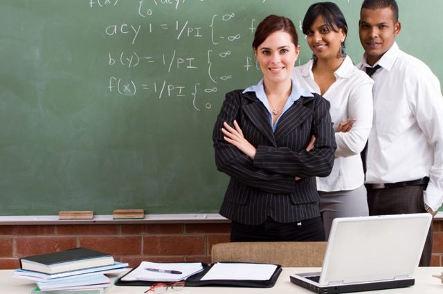 three diverse teachers stand together in front of chalkboard