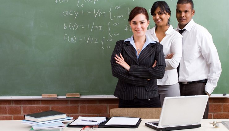 three diverse teachers stand together in front of chalkboard