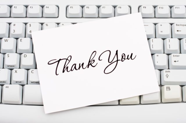 A thank you card sitting on a computer keyboard