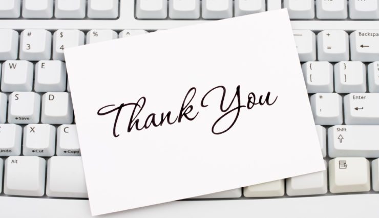 A thank you card sitting on a computer keyboard