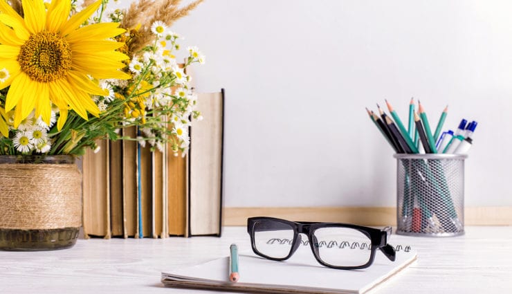 Books, glasses, markers and a bouquet of flowers in a vase on white board background. Concept for teachers day and first September